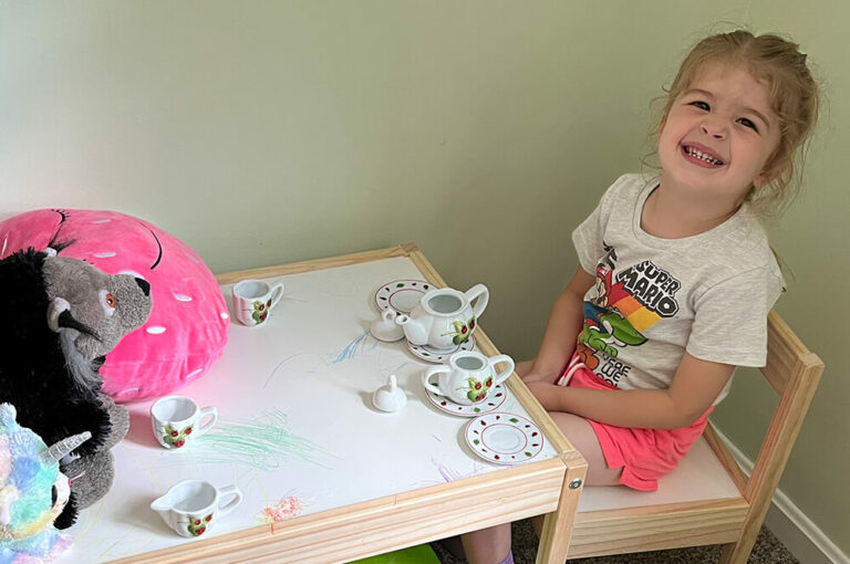 Girl having tea party with stuffed animals